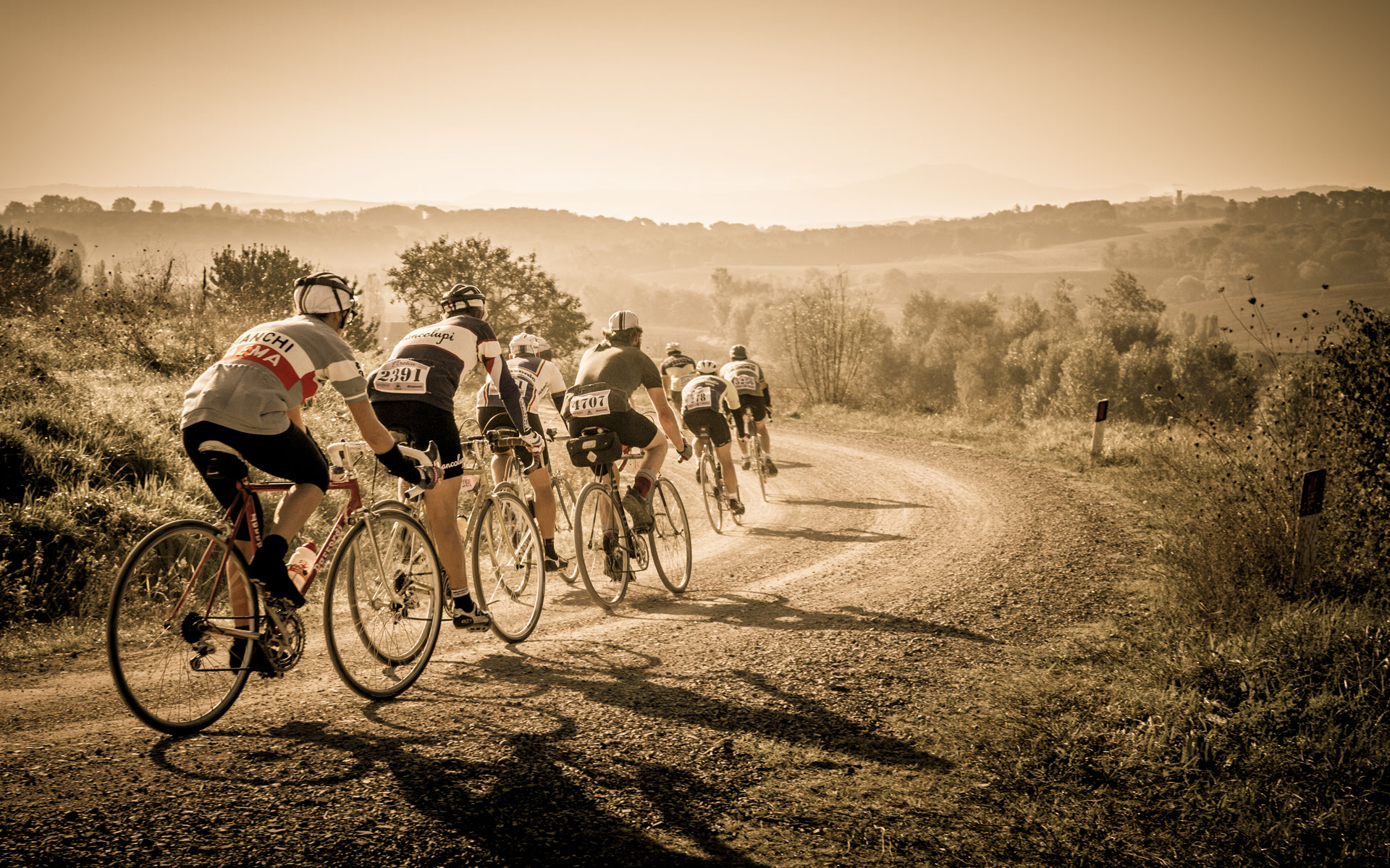 L'Eroica 2014 Foto Gruppo di Biciclette su Strada Bianca su Sfondo Panoramico Toscano